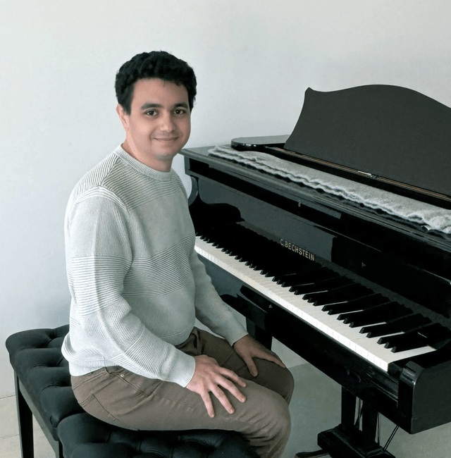 Ralph Betesh seated at a C. Bechstein grand piano.